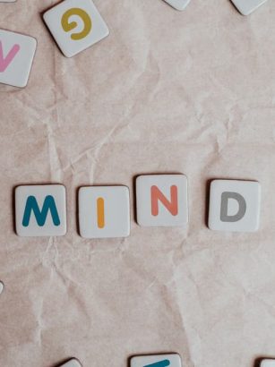 Close-up of scattered letter tiles spelling 'mind' on crumbled paper background.