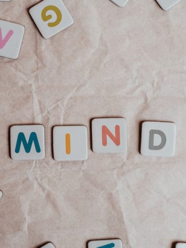 Close-up of scattered letter tiles spelling 'mind' on crumbled paper background.