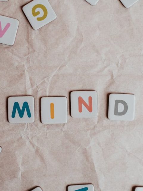 Close-up of scattered letter tiles spelling 'mind' on crumbled paper background.
