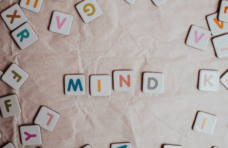 Close-up of scattered letter tiles spelling 'mind' on crumbled paper background.